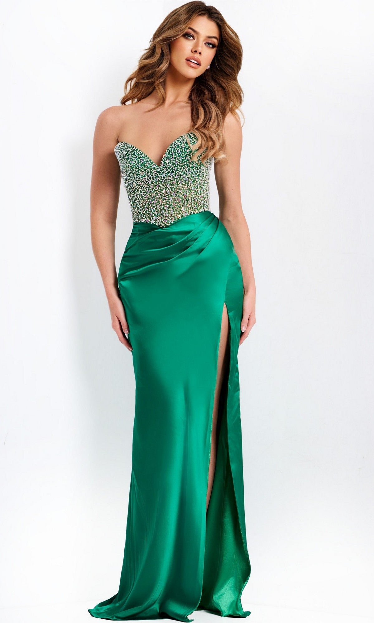 A woman stands against a plain white background wearing the Jovani 42845, a strapless green prom dress with a beaded corset bodice and satin sheath skirt featuring a high leg slit.
